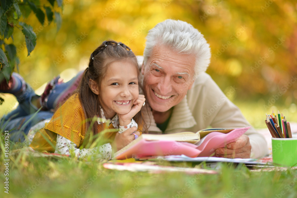 Grandfather and  granddaughter reading book