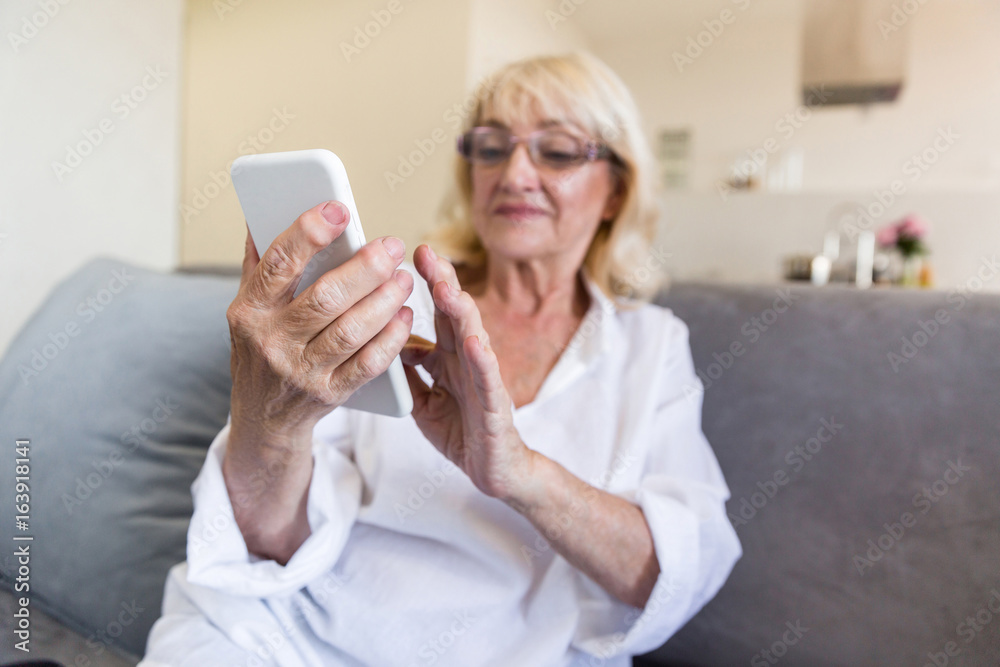 Beautiful senior woman in eyeglasses using a smartphone Beautiful senior woman in eyeglasses using a smartphone