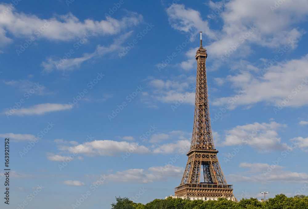 Eiffel tower against blue sky with clouds