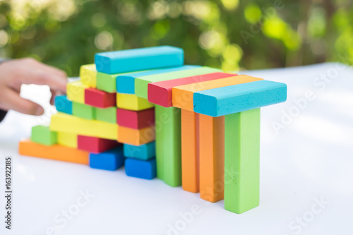 Closeup of asian kid's hand playing colorful wood blocks stack game, education and delelopment concept photo