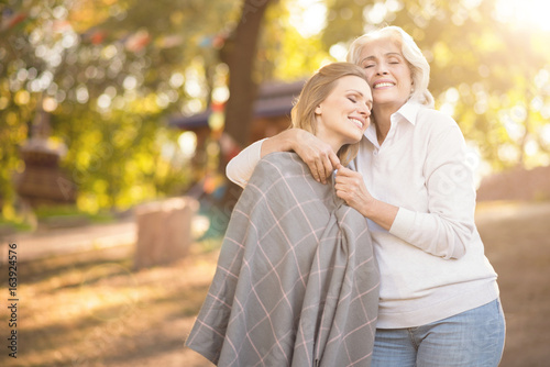 Upbeat woman hugging mature daughter in the park