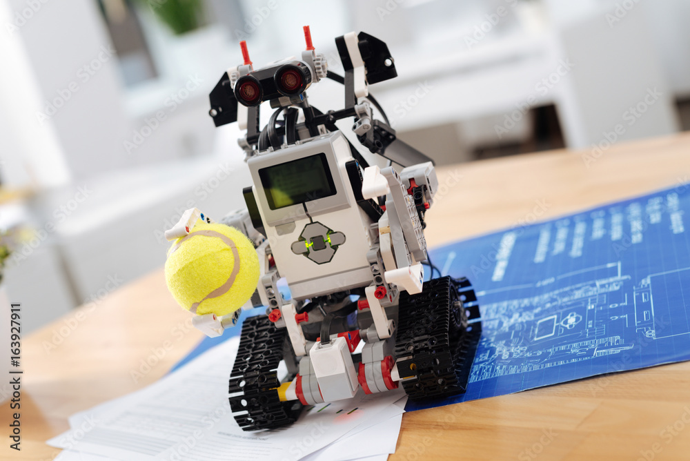 Cool robot holding tennis ball indoors