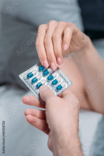 cropped shot of female and male hands holding medicines together