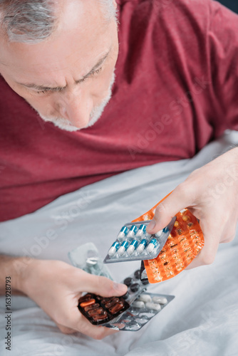 close up view of sick man holding medicines in hands
