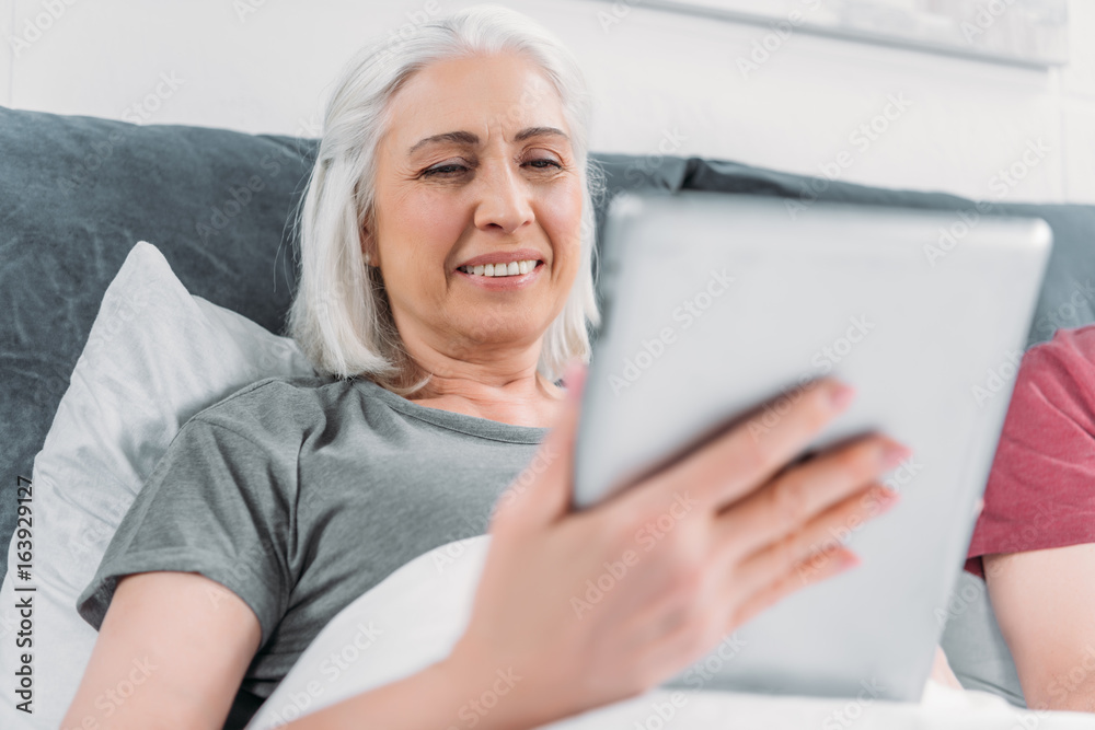 portrait of smiling woman using tablet while lying in bed at home portrait of smiling woman using tablet while lying in bed at home