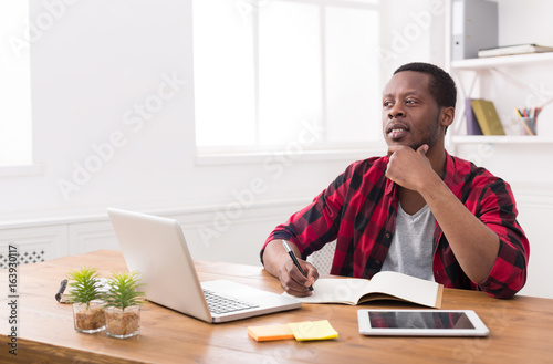 African american businessman using laptop and making notes