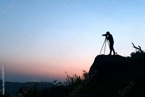 silhouette of photographer taking photo in the mountain and sunset .