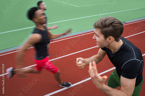 Trainer screaming near young multiethnic athlete men run © Drobot Dean