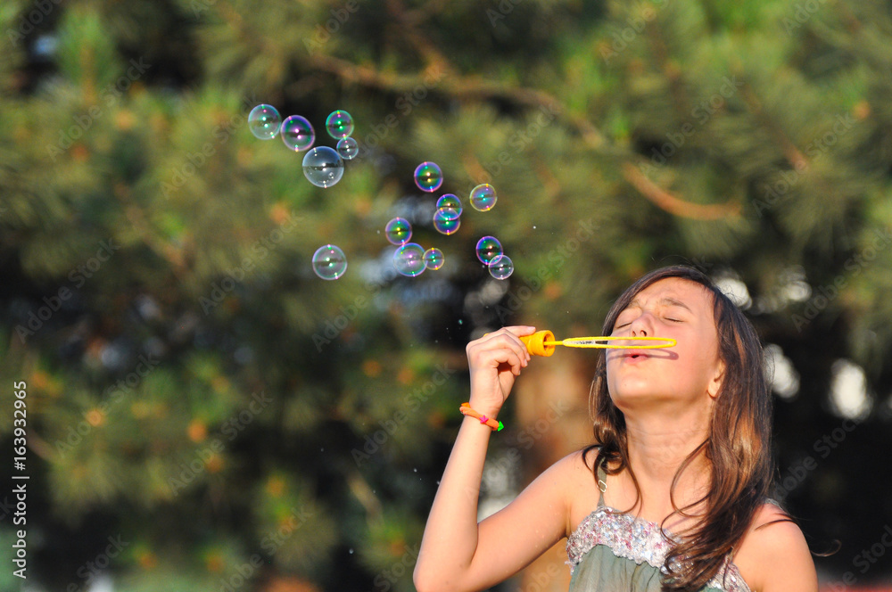 Adorable girl blowing soap bubbles in summer park. Girl play in park and blowing soap bubbles Adorable girl blowing soap bubbles in summer park. Girl play in park and blowing soap bubbles