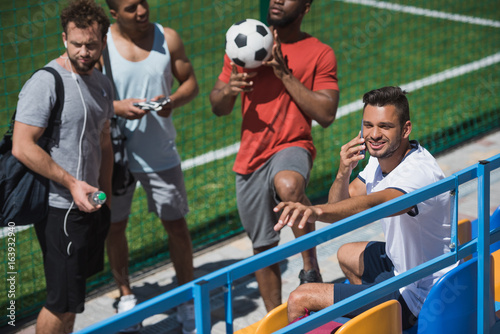 multicultural soccer team resting on stadium together before game