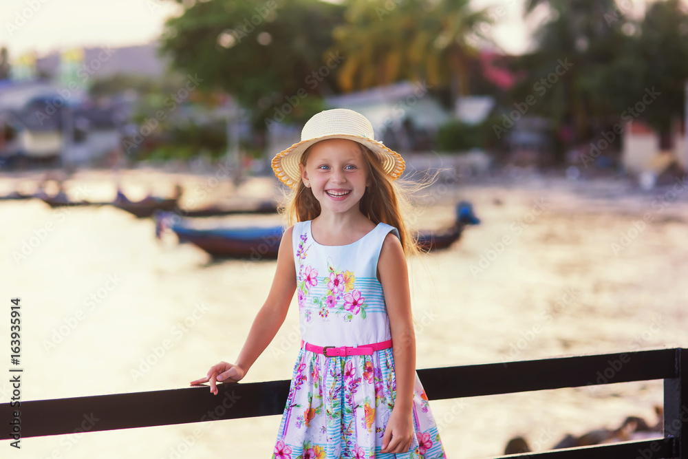 Sweet girl in a hat on vacation in the evening at sunset background