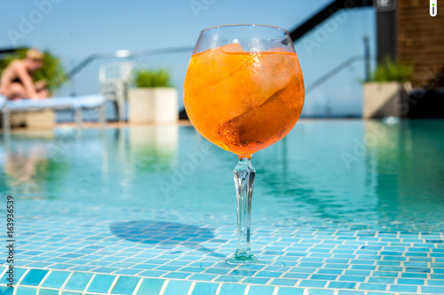 Fototapeta Naklejka Na Ścianę i Meble -  Cold cocktail aperol spritz on the edge of the pool.jpg