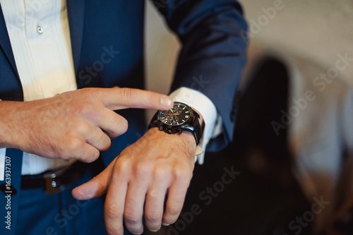 A man putting on watch. The bridegroom at the wedding with the clock
