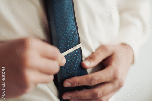 The groom in a suit corrects a tie. Groom's accessories