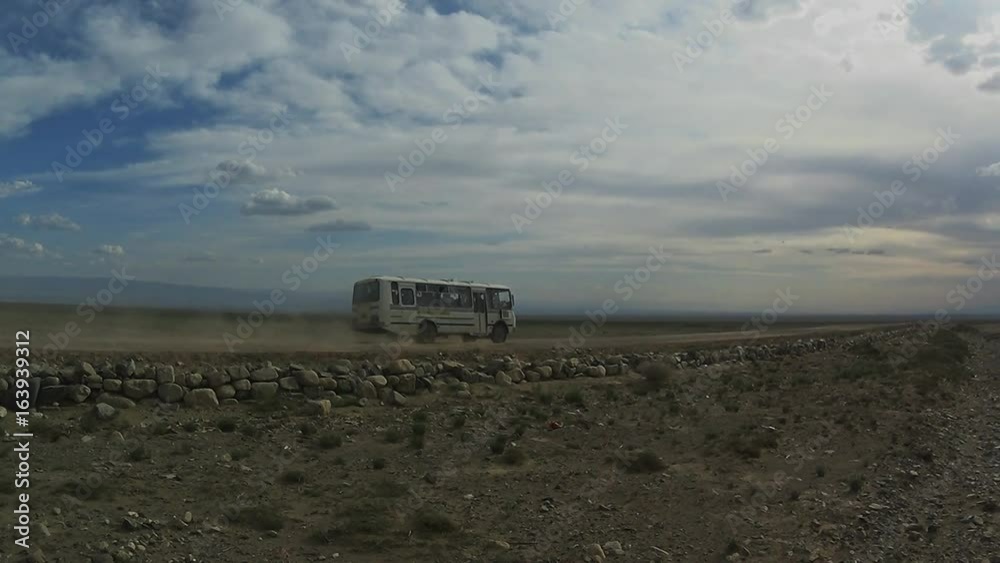 Bus Leaves Far Into the Distance Under Beautiful Clouds Along a Stony Dirt Road in the Desert of Mongolia Bus Leaves Far Into the Distance Under Beautiful Clouds Along a Stony Dirt Road in the Desert of Mongolia