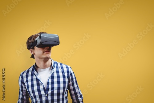 Man in VR headset looking up against yellow background