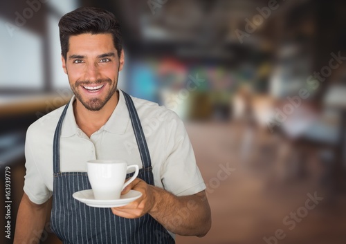 Cafe owner handing out cup of coffee against blurry cafe