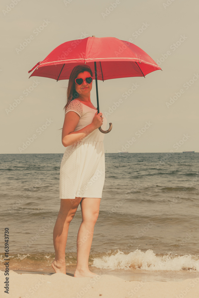 Redhead woman walking on beach holding umbrella Redhead woman walking on beach holding umbrella