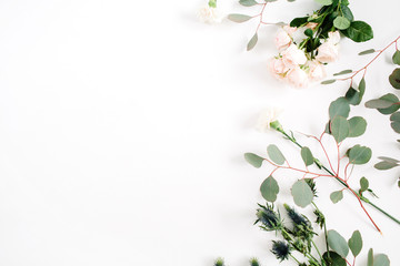 Beige rose flowers, eringium flower, eucalyptus branches on white background. Flat lay, top view. Floral background
