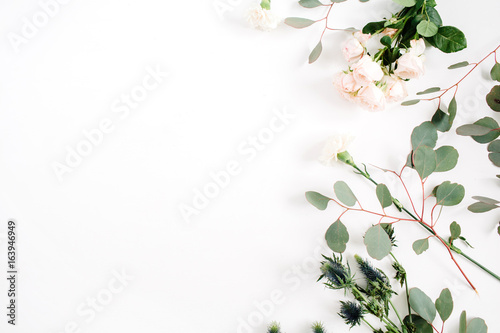 Beige rose flowers, eringium flower, eucalyptus branches on white background. Flat lay, top view. Floral background