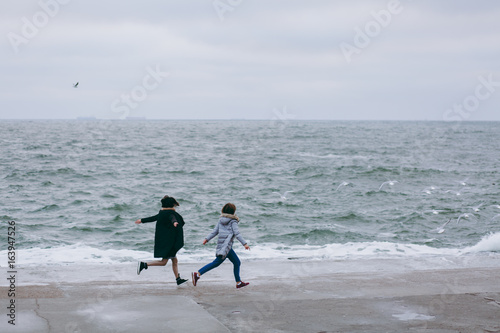 Happy, young couple is running on the beach in spring © ViDi Studio