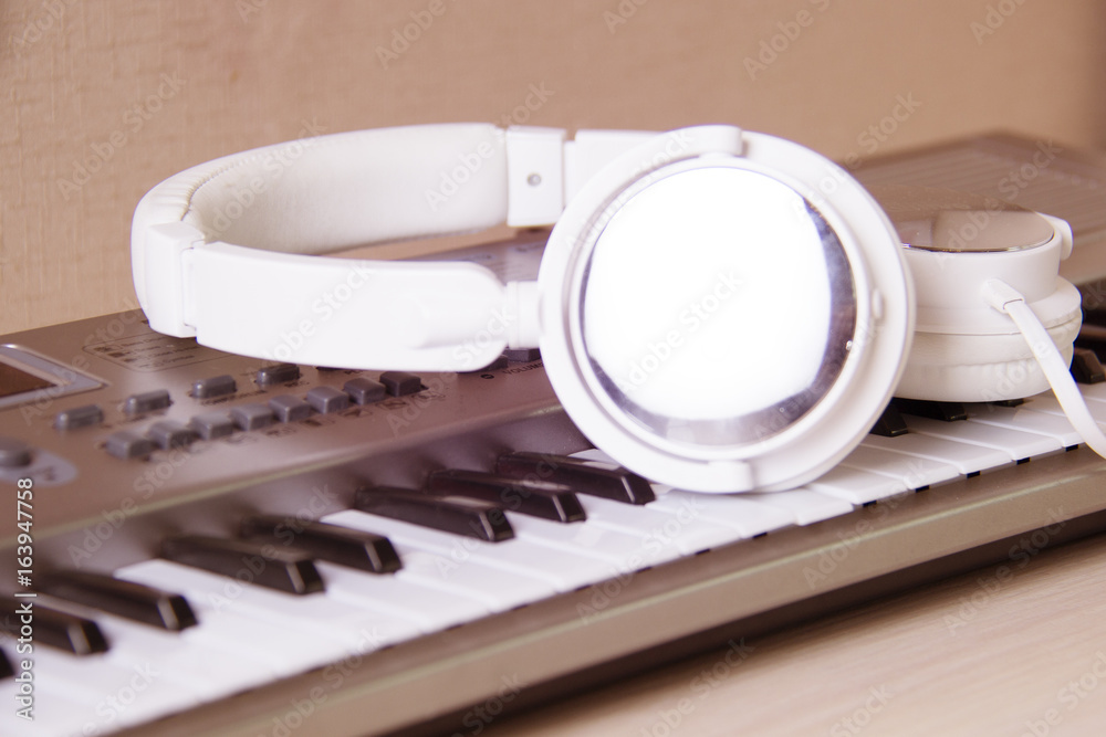 Headphones on musical synthesizer keyboard. Headphones on electronic piano. Headphones on musical synthesizer keyboard. Headphones on electronic piano.