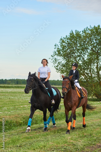 Pretty little girl jockey and her coach ridding a horse © Alex Shadrin