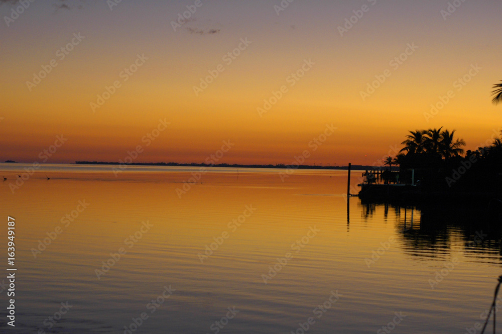twilight over ocean by dock orange and yellow skies