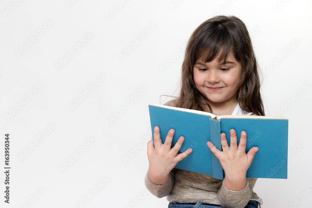Front view of smiling little girl reading a book Front view of smiling little girl reading a book