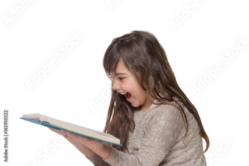 Laughing little girl leaning over an open book