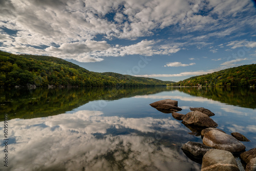 Photography beautiful mountain lake in New England with a rock jetty and reflections of fore