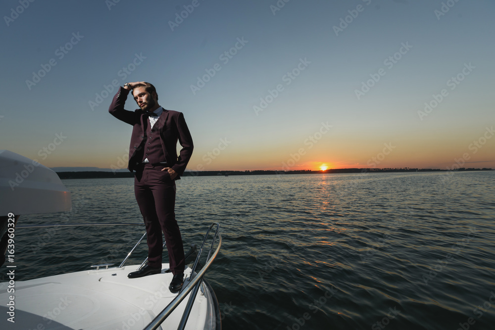 Fototapeta premium Handsome man on sailing boat in sunset.