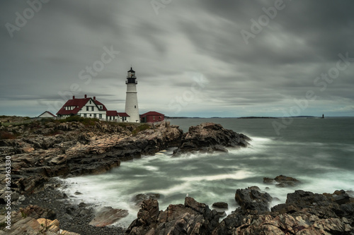 a lighthouse on the coast of New England under a cloudy sky during bad weather