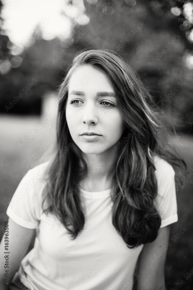 Black-and-white closeup portrait of pensive thinking dreaming young beautiful Caucasian woman girl with messy hair in park outside on summer day Black-and-white closeup portrait of pensive thinking dreaming young beautiful Caucasian woman girl with messy hair in park outside on summer day