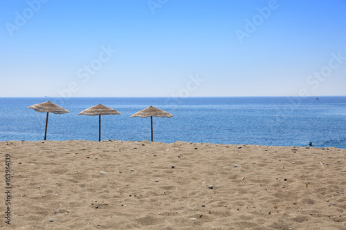 Trzy parasole na tropikalnej plaży wyspy Rodos w Grecji.