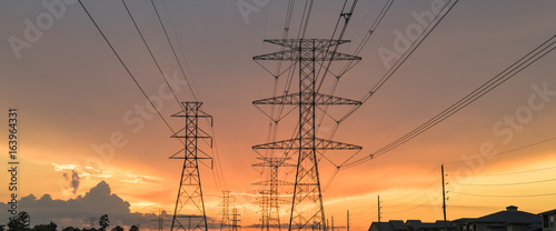 Group silhouette of transmission towers (power tower, electricity pylon, steel lattice tower) at twilight in US. Texture high voltage pillar, overhead power line, industrial background. Panorama style