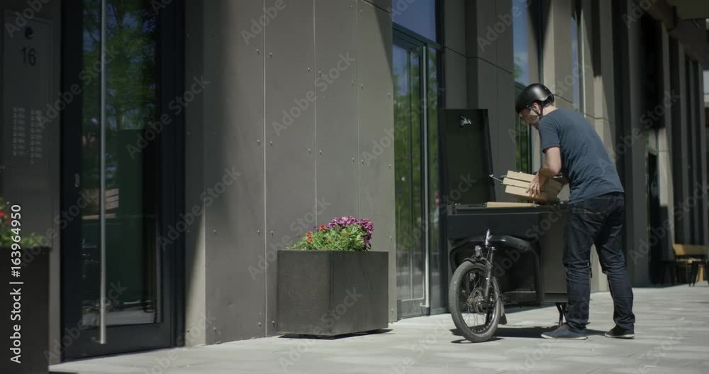 Handsome bike courier unloads his cargo bike Handsome bike courier unloads his cargo bike