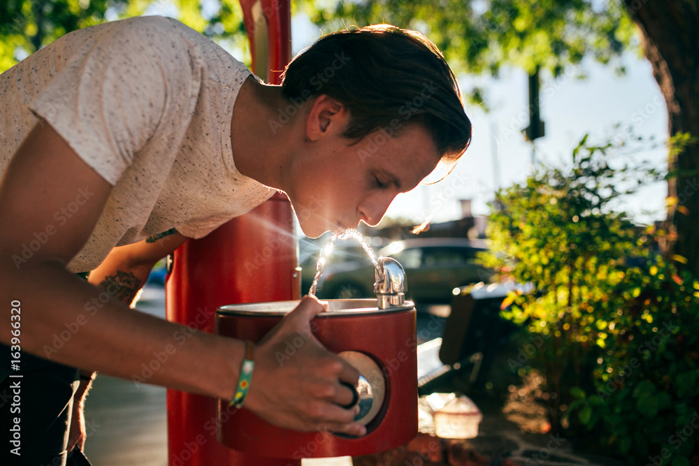Ταπετσαρία Cute handsome american young hipster teenager man in white tshirt drinks water f