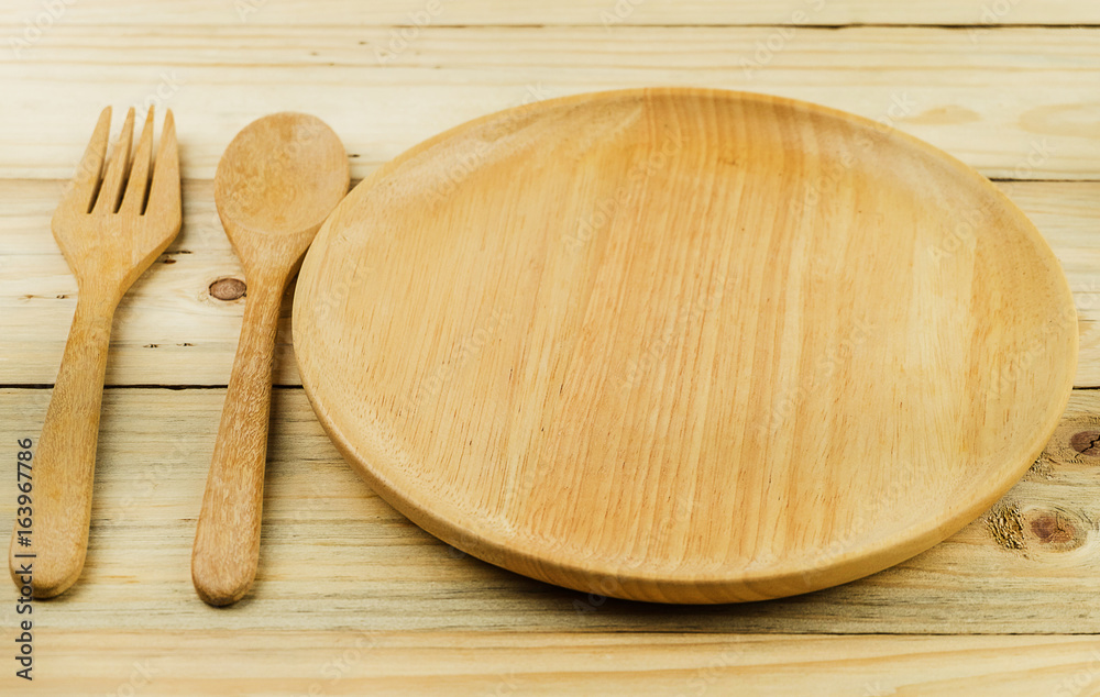 Wooden plate, wooden fork and wooden spoon on wooden talbe Wooden plate, wooden fork and wooden spoon on wooden talbe
