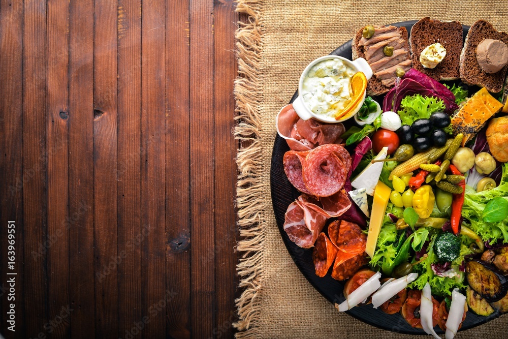 Set snacks with meat and pickled vegetables. Italian cuisine. Top view. On Wooden background. Set snacks with meat and pickled vegetables. Italian cuisine. Top view. On Wooden background.
