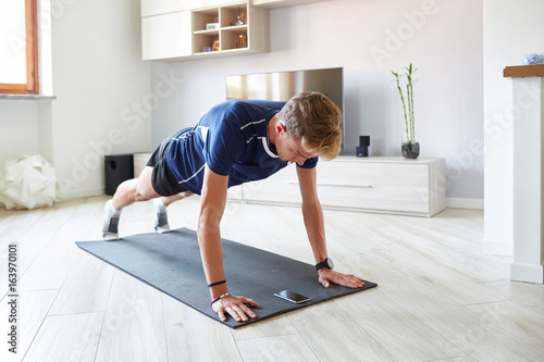 Ragazzo fitness a casa smartphone pettorali photo