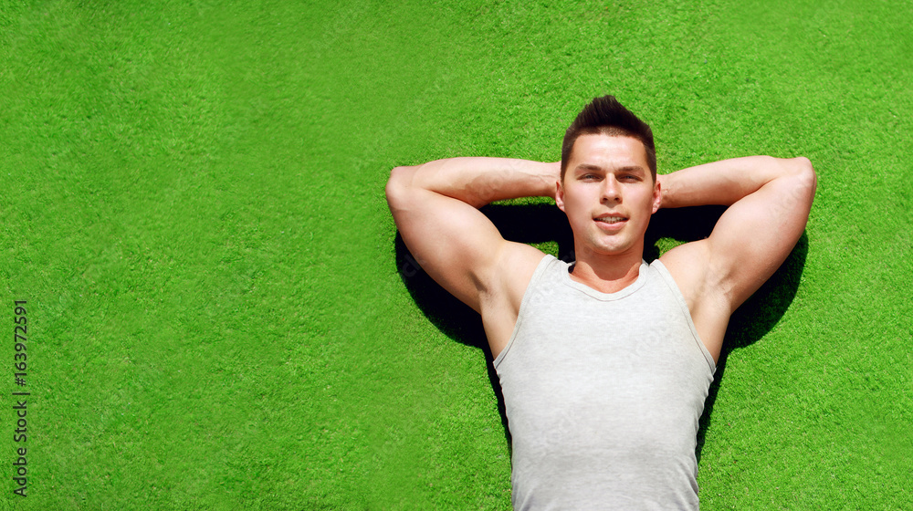 Fitness, sport concept - sportsman relaxing lying on the grass, handsome man resting or think, top view, empty copy space Fitness, sport concept - sportsman relaxing lying on the grass, handsome man resting or think, top view, empty copy space