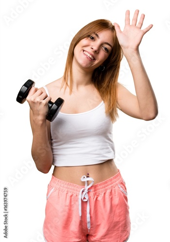 Beautiful sport woman with dumbbells saluting