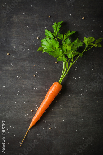 Carrot vegetable with green leaves on black wooden table. Top view. Copy space.