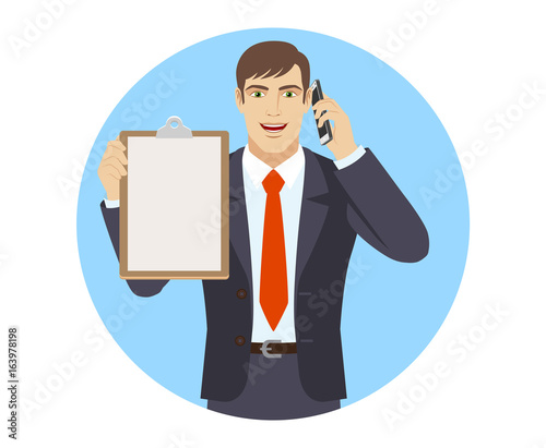 Businessman talking on the mobile phone and holding the clipboard