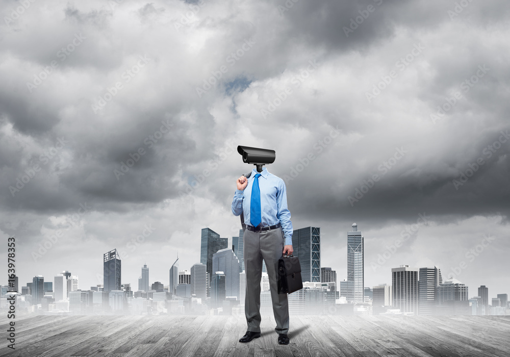 Camera headed man standing on wooden floor against modern cityscape Camera headed man standing on wooden floor against modern cityscape