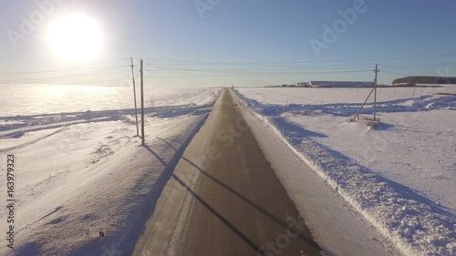 Aerial Roadways. Suv driving in white snowy evergreen forest on slippery asphalt road. Aerial view of the road and the fields in the winter photo