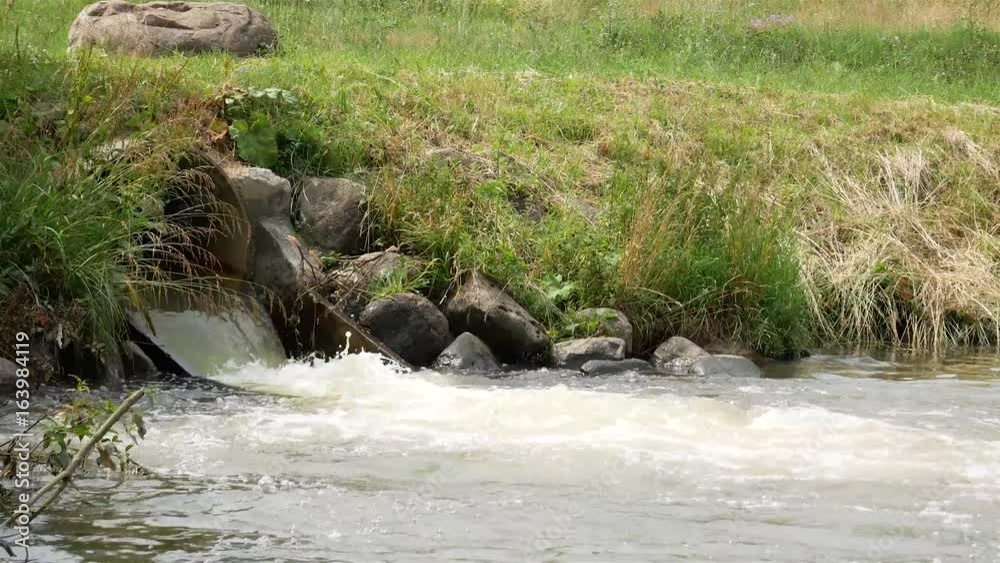 Dirty sewage yellow waters of production flow from pipe to river