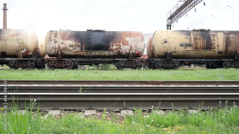 Railway, rails. Dirty freight cars and cisterns move in the background Railway, rails. Dirty freight cars and cisterns move in the background