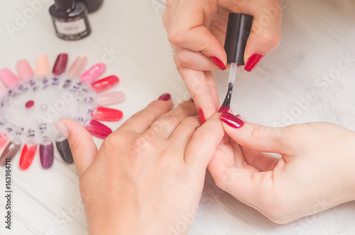 Master of manicure paints nails with red lacquer
